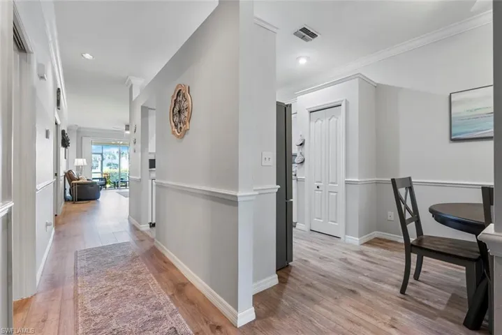 Corridor with ornamental molding and light wood-type flooring