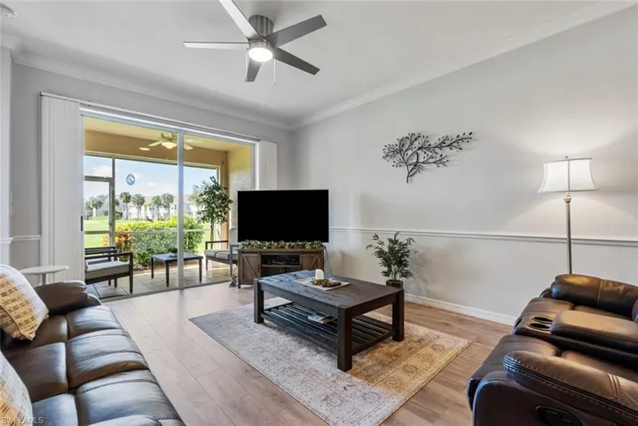 Living room featuring light hardwood / wood-style floors, crown molding, and ceiling fan