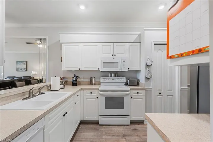 Kitchen featuring white cabinets, light wood-type flooring, and white appliances