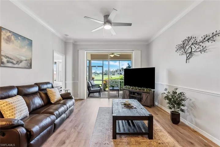Living room with crown molding, light wood-type flooring, and ceiling fan