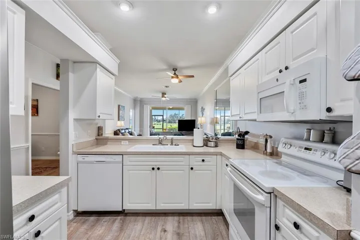 Kitchen featuring light hardwood / wood-style flooring, ornamental molding, sink, white cabinetry, and white appliances