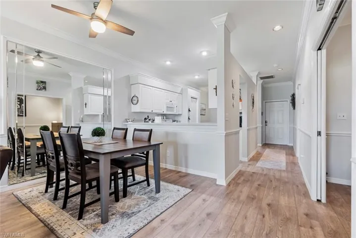 Dining area with light hardwood / wood-style floors, ornamental molding, and ceiling fan