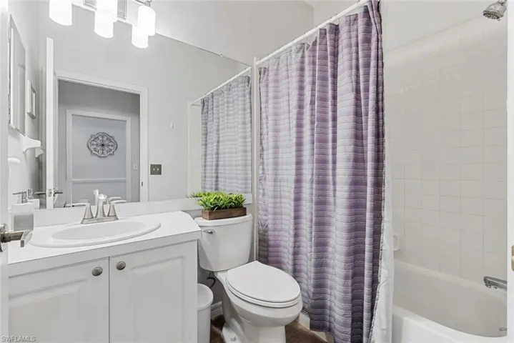 Full bathroom with toilet, shower / tub combo with curtain, and vanity