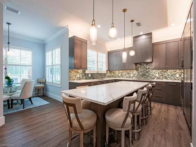 Kitchen featuring wall chimney range hood, dark hardwood / wood-style floors, dark brown cabinetry, and a kitchen island