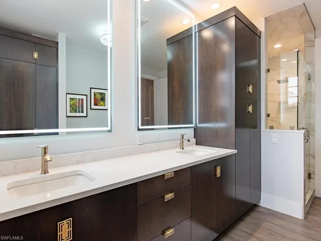 Bathroom with vanity, a shower with shower door, and wood-type flooring