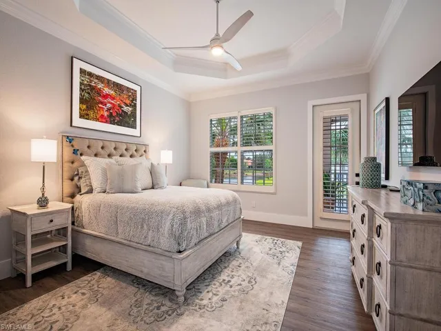 Bedroom featuring ceiling fan, access to outside, dark hardwood / wood-style flooring, a raised ceiling, and ornamental molding