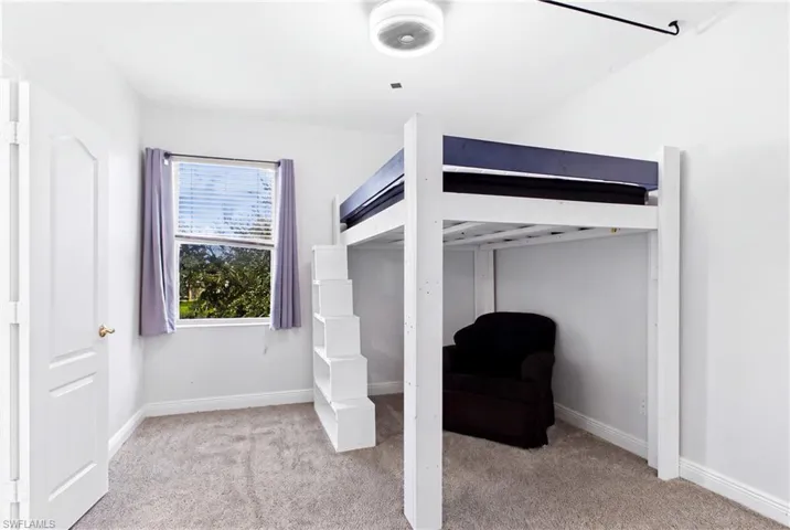 Neutral-toned carpeting, single-pane window with white trim, white-painted interior door, and modern flush-mount overhead lighting