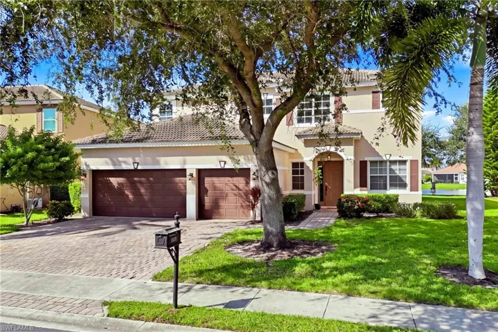 Two-story residence featuring a tile roof, paver driveway, multi-car garage, and shuttered windows