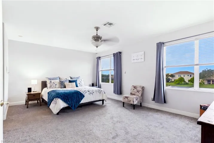 Spacious room featuring neutral carpeting, a brushed metal ceiling fan with integrated lighting, and multiple windows with white horizontal blinds
