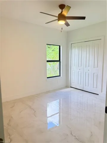 Unfurnished room featuring light marble finish flooring and ceiling fan