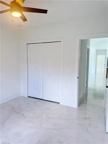 Unfurnished bedroom with light marble finish flooring, a closet, and ceiling fan