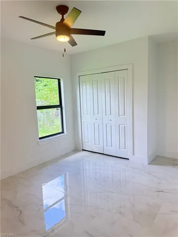 Bathroom with a marble finish shower, light marble finish floors, and recessed lighting