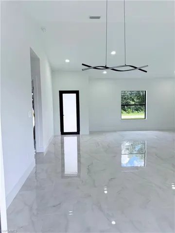 Kitchen featuring appliances with stainless steel finishes, light stone countertops, and white cabinetry