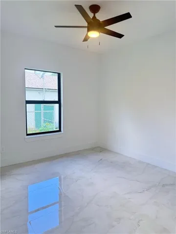 Empty room featuring ceiling fan and light marble finish floors
