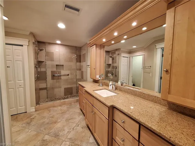 Bathroom with tile flooring, walk in shower, ornamental molding, and large vanity