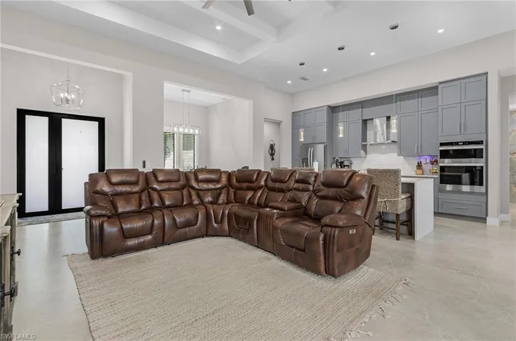 Living room with a chandelier, beam ceiling, recessed lighting, a high ceiling, and a ceiling fan