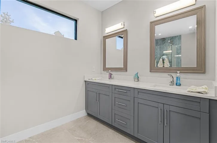 Full bathroom featuring double vanity, a shower with door, and marble finish flooring