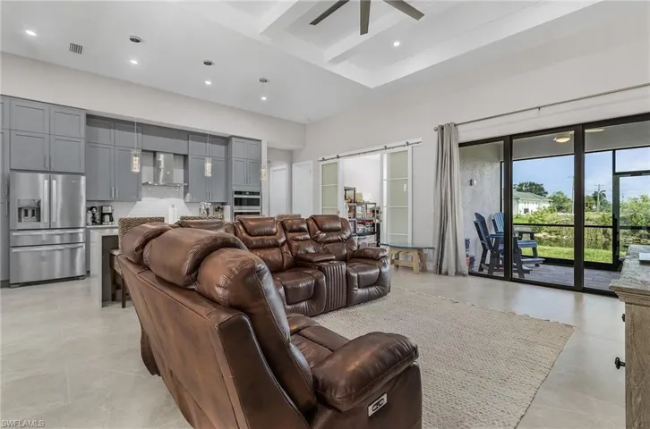 Living room featuring a high ceiling, a ceiling fan, recessed lighting, and beamed ceiling