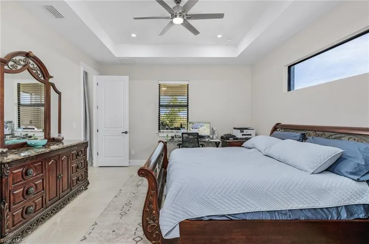 Bedroom featuring a raised ceiling, multiple windows, ceiling fan, and recessed lighting