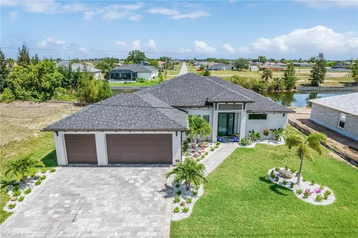 View of front of property featuring a garage, decorative driveway, a shingled roof, and a front lawn
