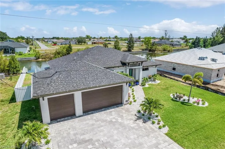 View of front of home with a shingled roof, a garage, decorative driveway, a residential view, and a water view