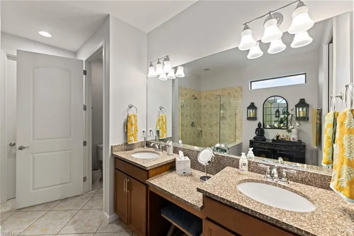Primary Bathroom featuring an enclosed shower, vanity, walk in closet, separate toilet room and tile floors