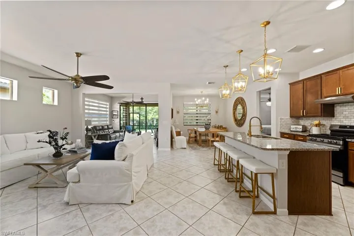 Kitchen with ceiling fan with notable chandelier, decorative light fixtures, backsplash, gas range, and sink