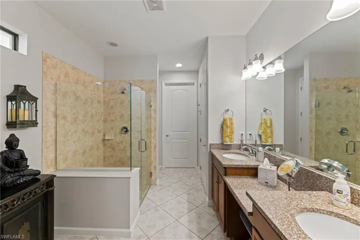 Primary Bathroom featuring dual bowl vanity, an enclosed shower, and tile floors