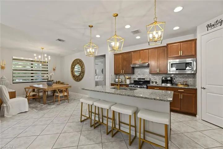Kitchen with hanging light fixtures, stainless steel appliances, backsplash, and sink