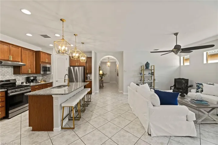 Kitchen with stainless steel appliances, an island with sink, backsplash, pendant lighting, and sink