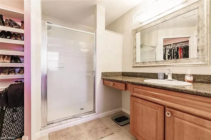 Bathroom with a spacious closet, a stall shower, vanity, and tile patterned floors