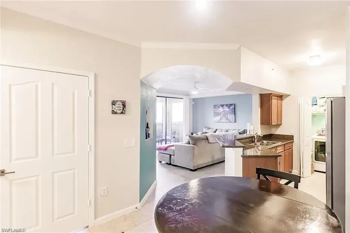 Dining room featuring ornamental molding, light tile patterned floors, arched walkways, and ceiling fan