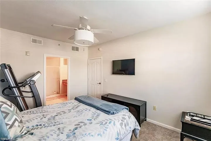 Bedroom with light carpet, ceiling fan, and ensuite bath
