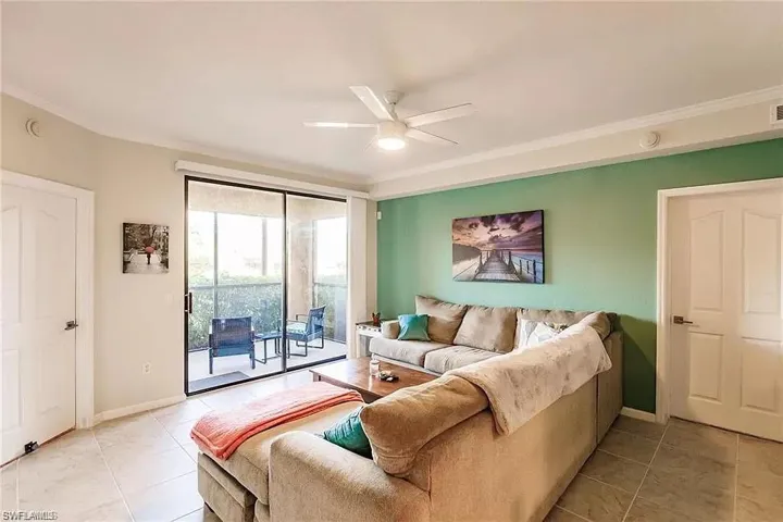 Living area with ceiling fan, light tile patterned flooring, and ornamental molding