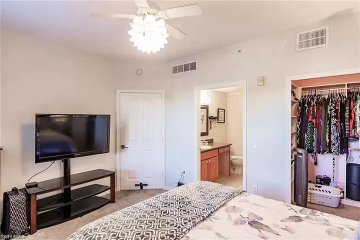 Bedroom featuring a closet, light carpet, connected bathroom, a spacious closet, and ceiling fan
