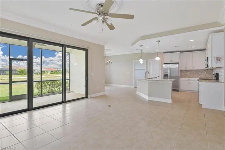 Open-concept living space with large format tile flooring, crown molding, and a ceiling fan