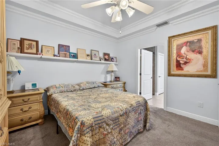 Bedroom with light colored carpet, crown molding, and ceiling fan