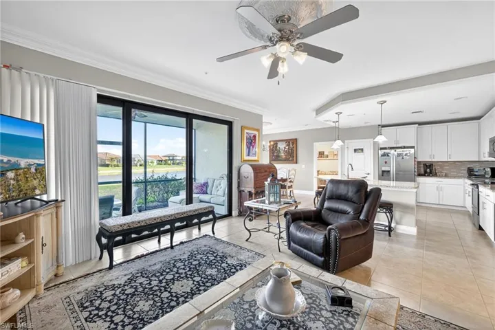 Living area with crown molding, a ceiling fan, a water view, and light tile patterned floors