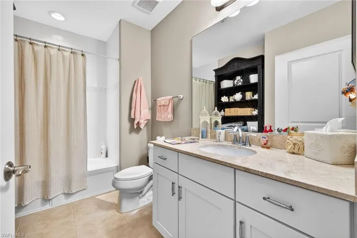 Bathroom featuring vanity, shower / bathtub combination with curtain, and light tile patterned floors