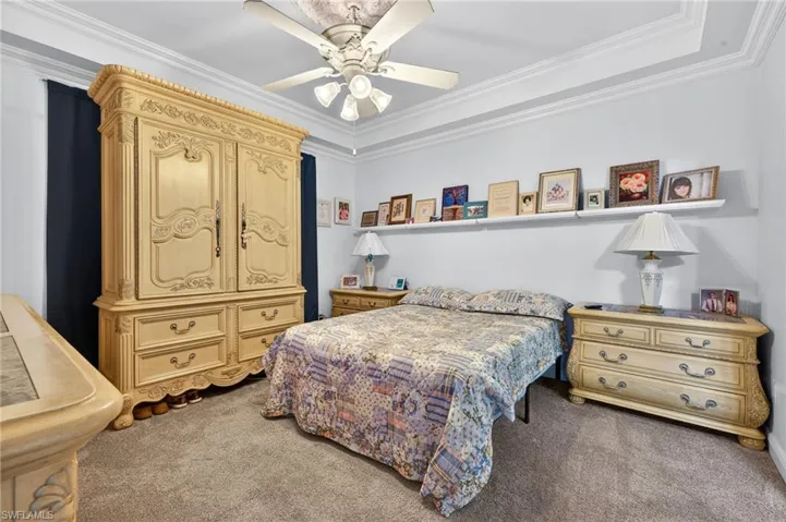Bedroom with crown molding, dark carpet, and a ceiling fan