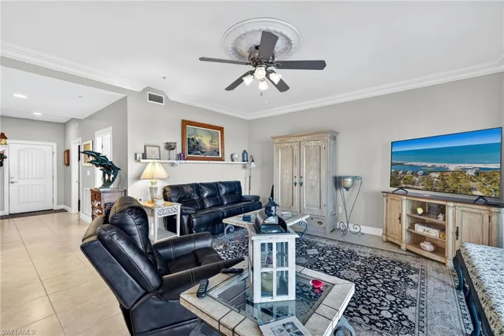 Living room with ornamental molding, ceiling fan, and light tile patterned floors