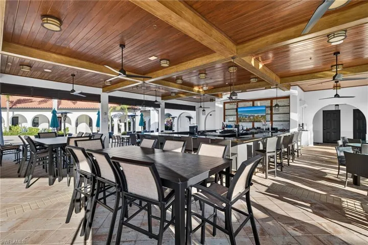 Dining space with ceiling fan, arched walkways, a wood ceiling with exposed beams, and stone tile flooring