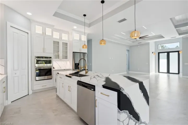 Kitchen featuring ceiling fan, a raised ceiling, white cabinetry, and appliances with stainless steel finishes