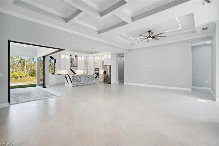 Unfurnished living room with beamed ceiling, ceiling fan, crown molding, and coffered ceiling