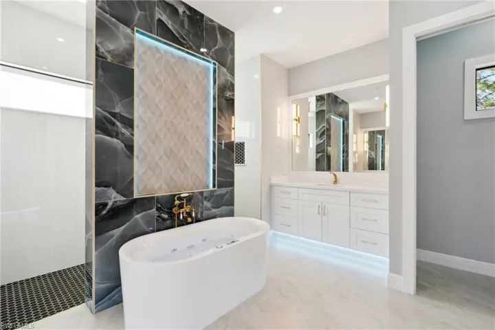 Bathroom featuring vanity and separate shower and tub