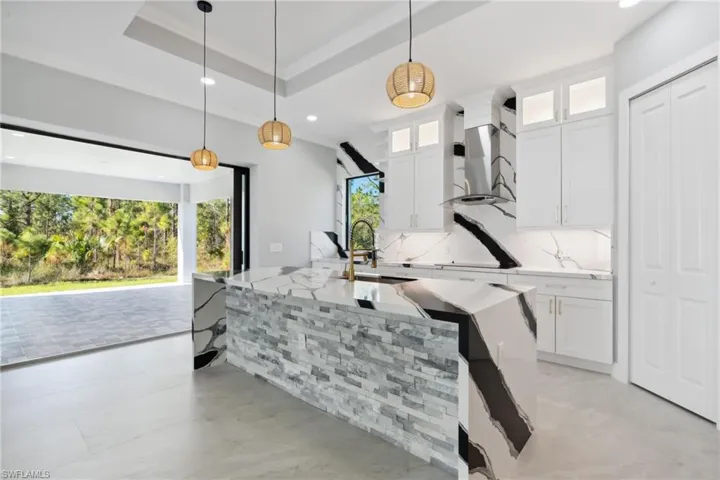 Kitchen with island range hood, white cabinets, and pendant lighting