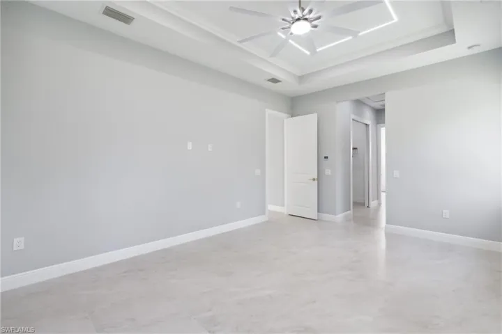 Unfurnished room featuring a tray ceiling, ceiling fan, and crown molding