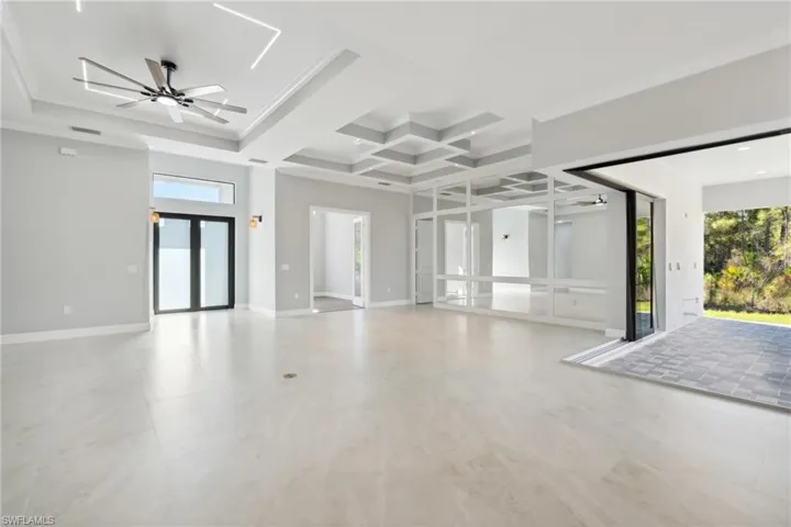 Spare room featuring beamed ceiling, crown molding, ceiling fan, and coffered ceiling