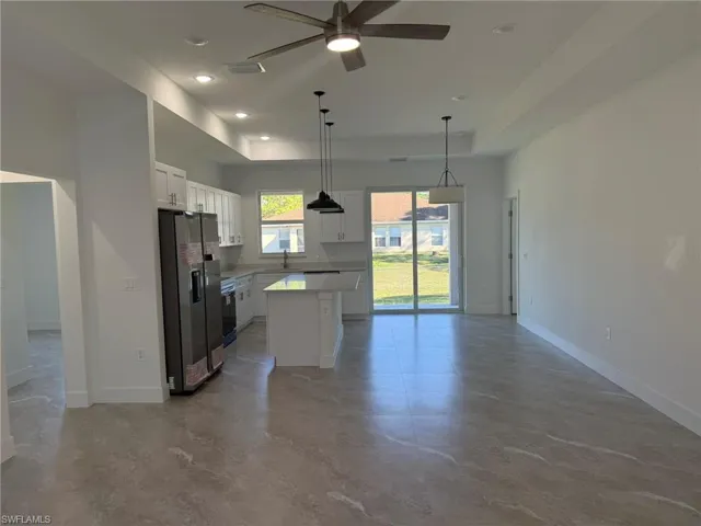 Kitchen featuring appliances with stainless steel finishes, a raised ceiling, open floor plan, white cabinets, and recessed lighting