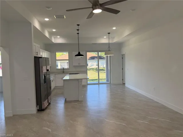 Kitchen with a raised ceiling, white cabinets, stainless steel fridge with ice dispenser, and recessed lighting